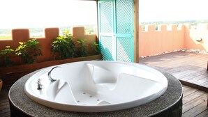 A spa area with a large white bathtub, wooden deck, and a view of the landscape. - Raid Gardden Boutique Hotel (Magong)