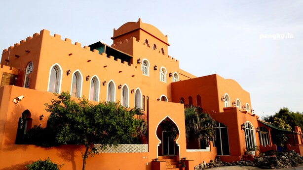 A large, orange building with multiple arched windows and a tower. - Raid Gardden Boutique Hotel (Magong)