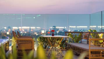 An outdoor seating area with wicker furniture and a table with a vase and two glasses.