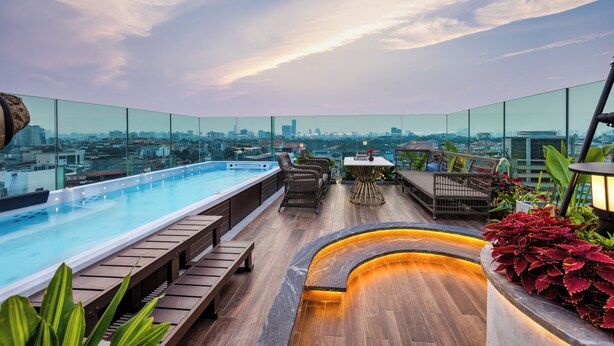 A rooftop pool area with a city view, wooden deck, and seating arrangements. -  Peridot Gallery Classic Hotel (Hanoi)