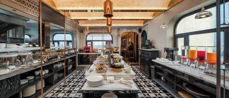 A modern kitchen with a checkered floor, marble countertops, and a central island with a tiered display of food.