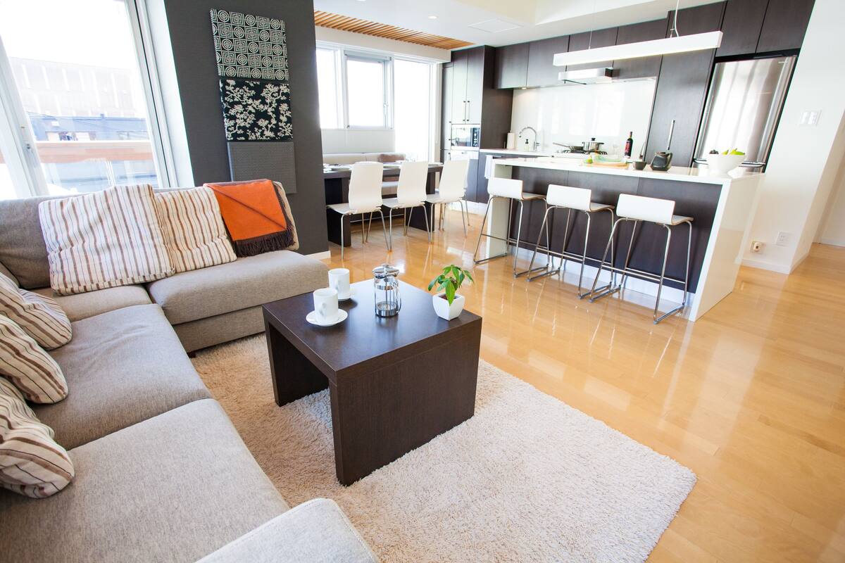 A modern living room with a sofa, a coffee table, and a dining area with chairs.