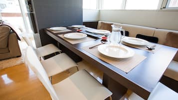 A dining area with a long table set for four, including plates, cutlery, and a pitcher.