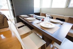 A dining area with a long table set for four, including plates, cutlery, and a pitcher. - Alpen Ridge (Kutchan)