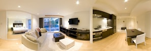 A modern living room with a sofa, coffee table, and a fireplace. There is a kitchen area with a dining table and chairs. - Alpen Ridge (Kutchan)