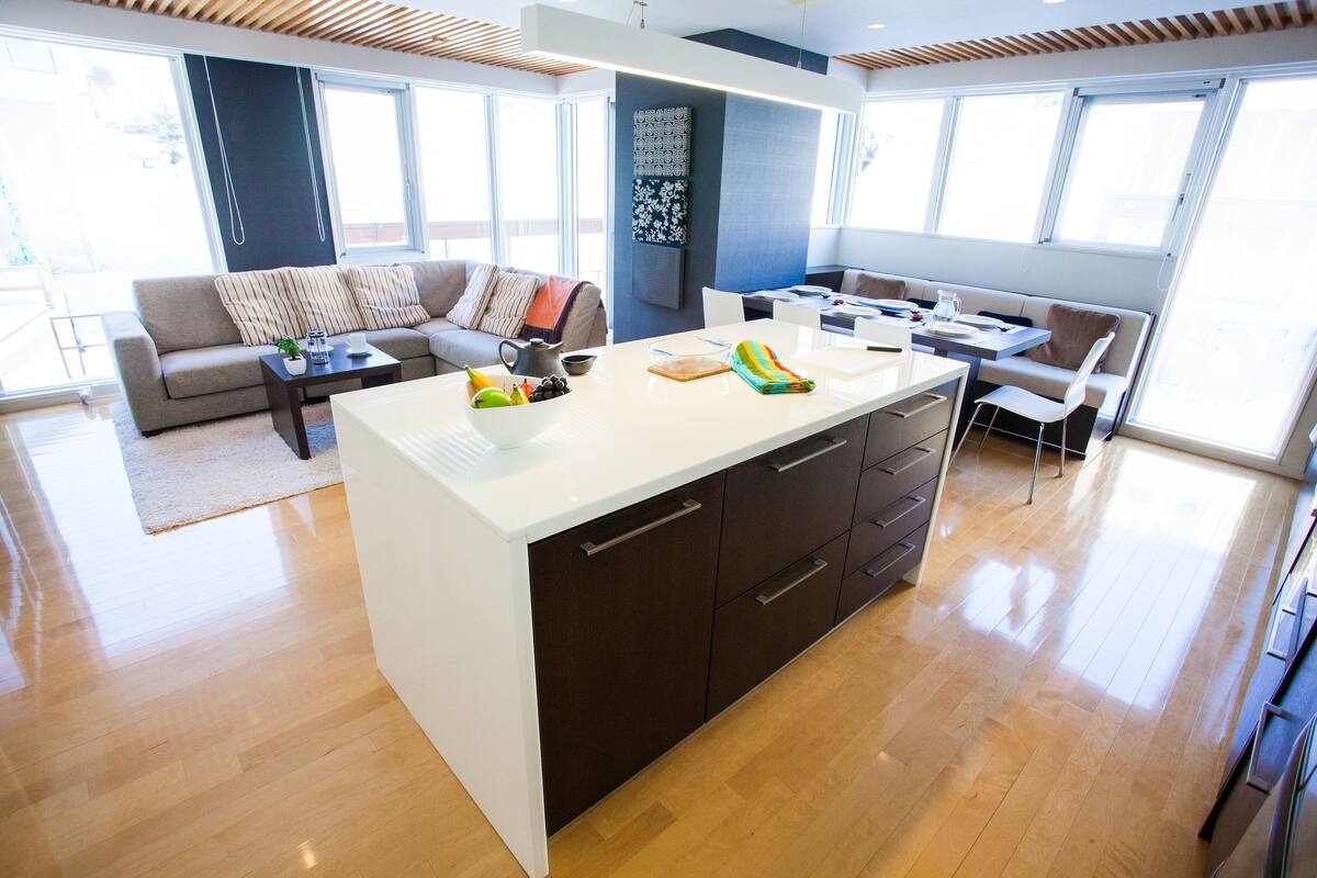 A modern kitchen with a central island, a dining area with a table and chairs, and a living area with a sofa and a coffee table.