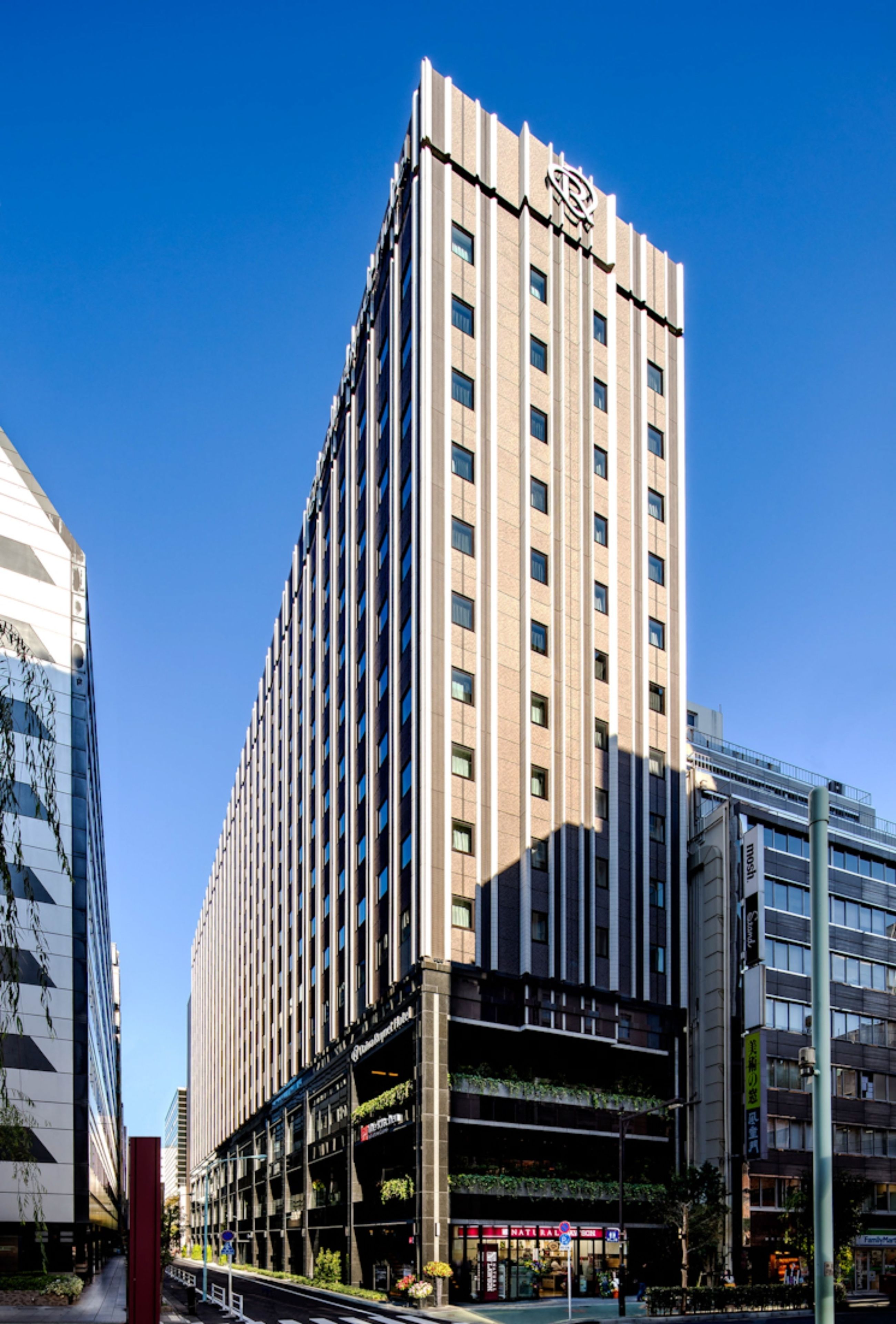A tall hotel with a modern design, featuring a prominent logo on the top.