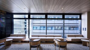 Un interior moderno con un amplio ventanal, techo de madera y una zona de estar con sofás y mesas.