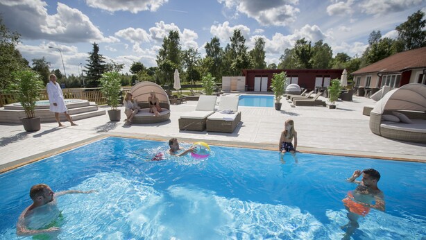Un área de piscina con sillas de descanso y un edificio pequeño al fondo.
