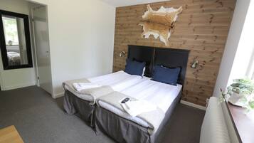 A neatly made bed with a headboard, a mirror, and a wall-mounted animal hide.