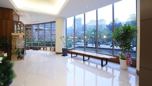 A spacious lobby with large windows, a wooden reception desk, and a bench.
