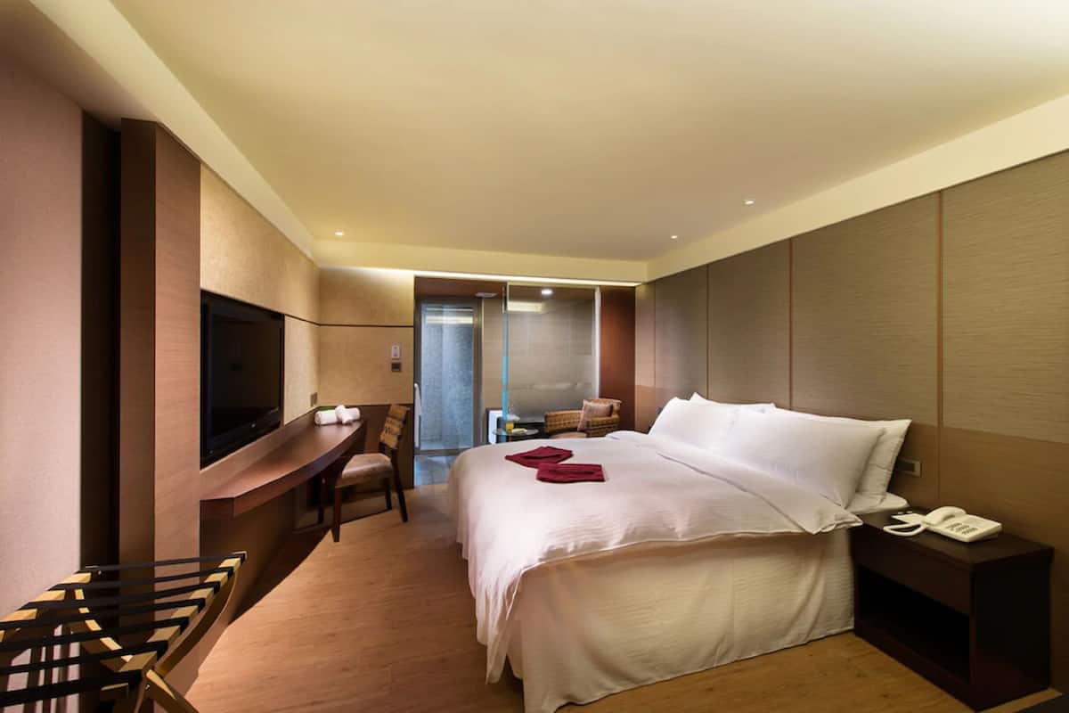 A hotel room with a bed, a TV, a desk, and a chair.
