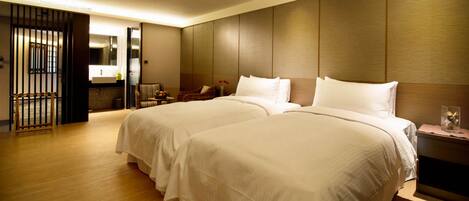 A hotel room with two large beds, a wooden floor, a modern bathroom, and a view of the outside.