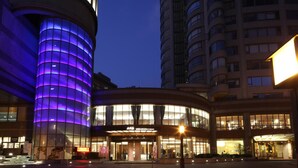 A hotel with a modern glass facade, a prominent entrance, and a curved structure to the left.
