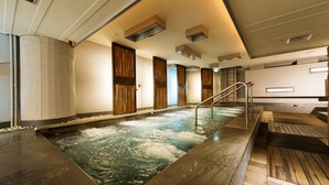A spa area with a hot tub, wooden flooring, and a staircase leading to an upper level.