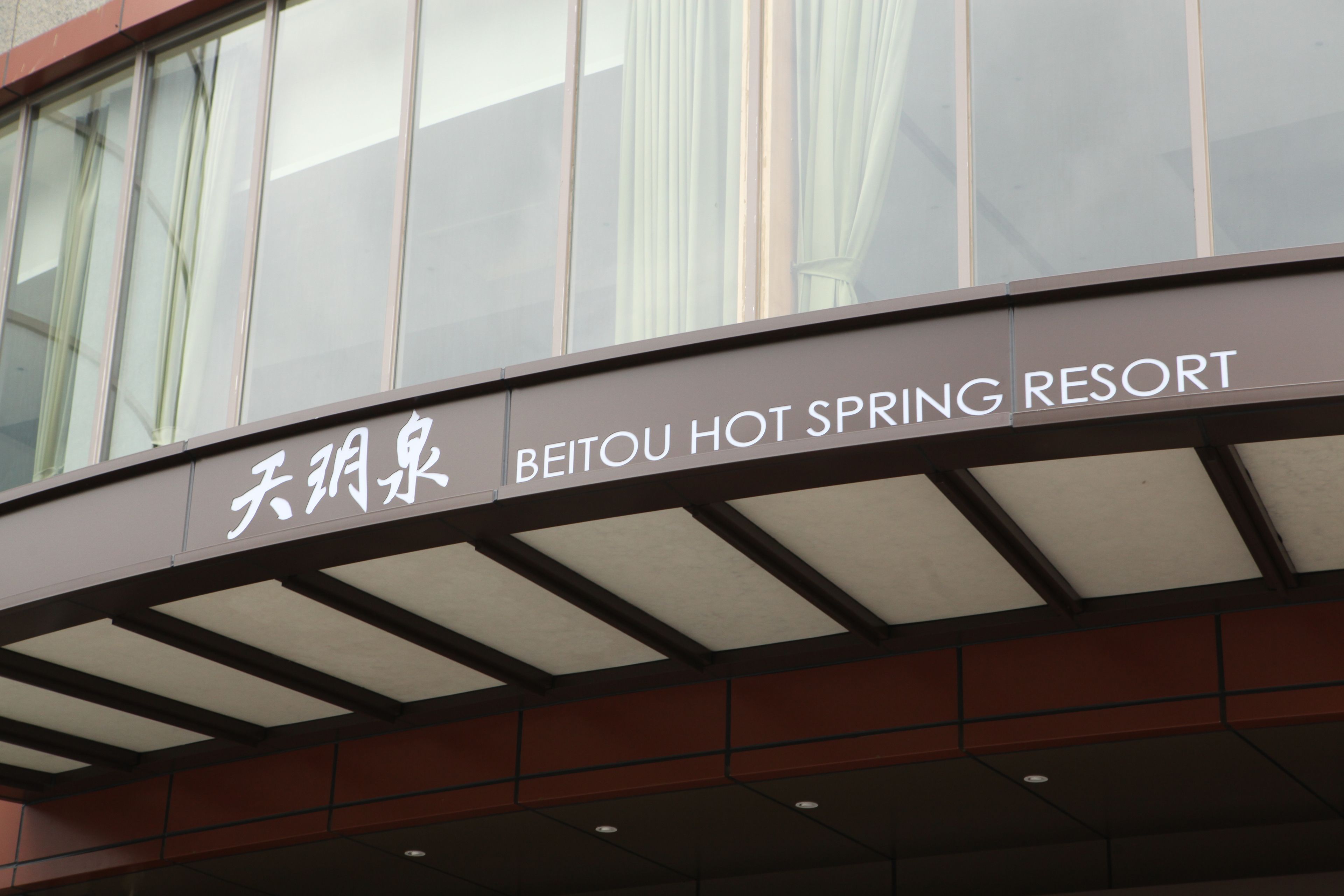 The exterior of Beitou Hot Spring Resort with a sign in both Chinese and English.