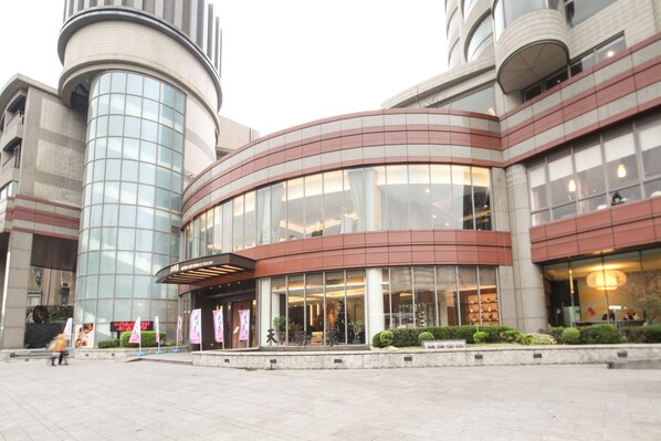 A modern hotel with a curved facade, large windows, and a central entrance.