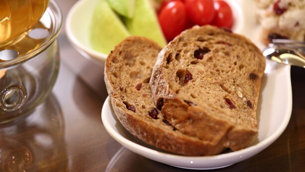 Slices of fruit bread on a plate with a glass of tea and some vegetables in the background. - Hualien Little Squirrel B&b (Hualien City)