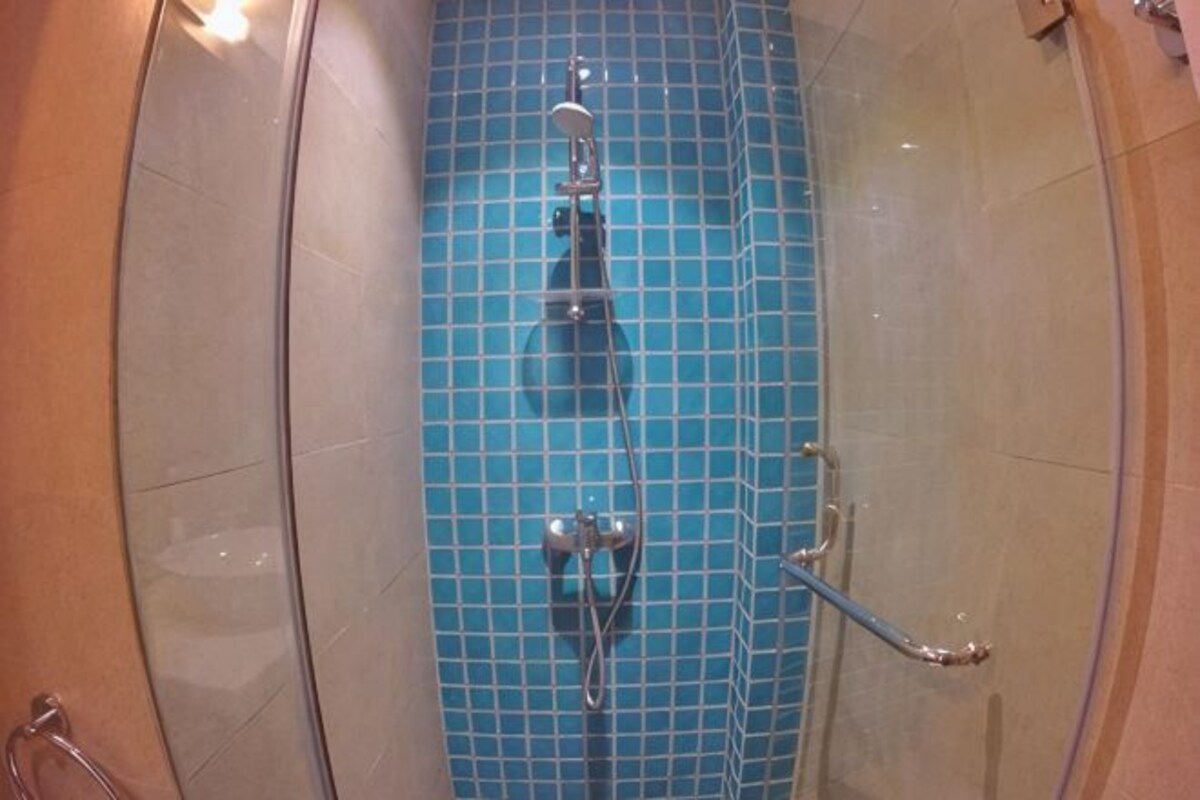Un baño con piso de azulejos azules, zona de ducha y puerta de vidrio.