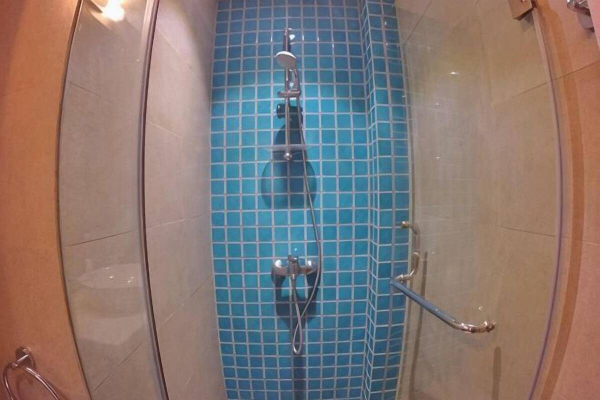 A bathroom with a blue tiled floor, a shower area, and a glass door.
