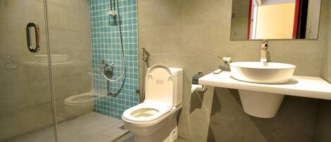 A modern bathroom with a glass-enclosed shower, a white toilet, and a sink with a mirror above it.