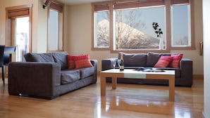 A living room with two sofas, a coffee table, and large windows with a view of a mountain. - Kamakura (Kutchan)