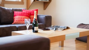A modern living room with a wooden coffee table, a bottle of champagne, and a glass. - Kamakura (Kutchan)