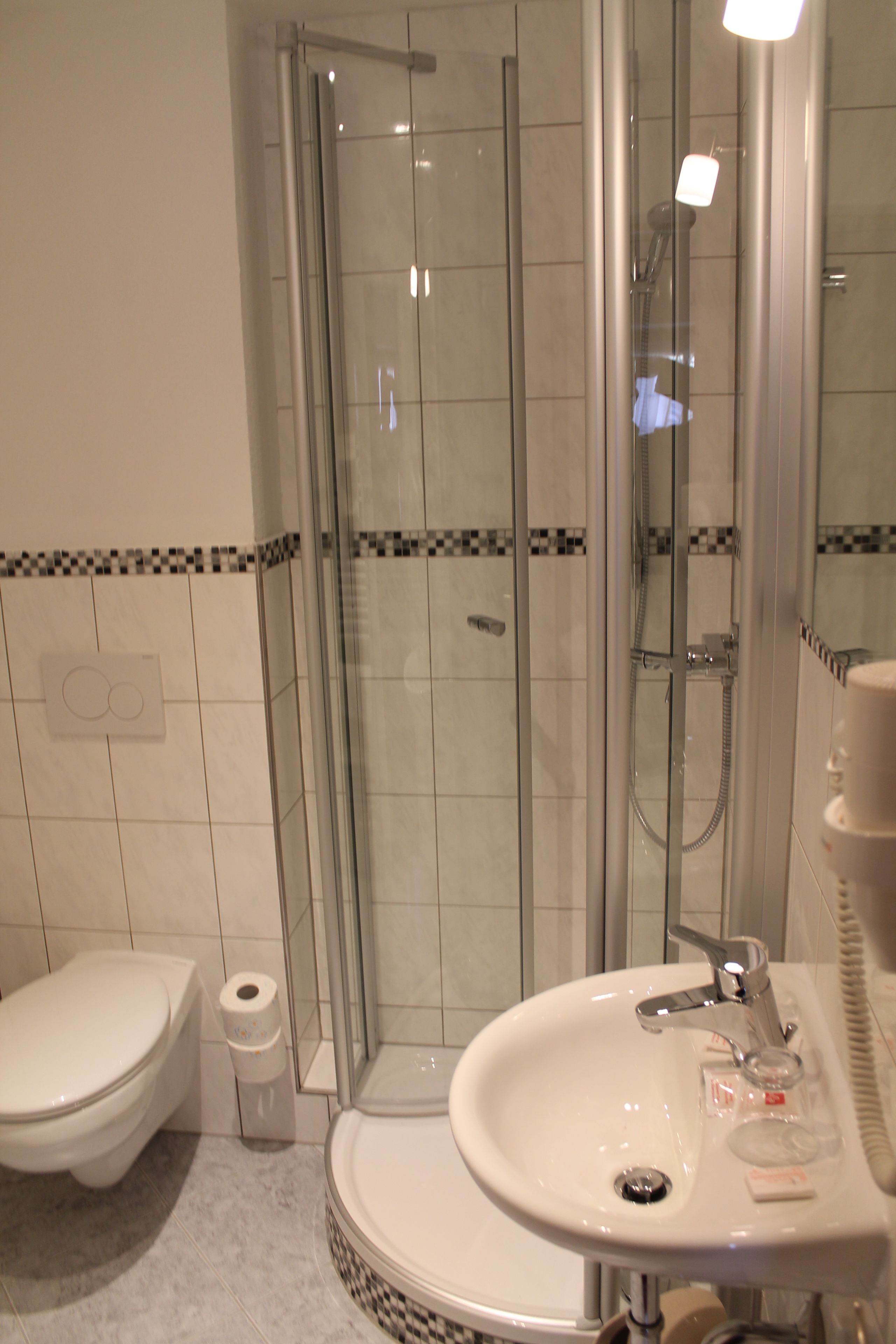 Ein Badezimmer mit einer Duschkabine, einem weißen Waschbecken und einer Toilette.