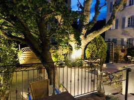 Un patio con una reja de hierro forjado, un banco de madera y una planta en maceta.