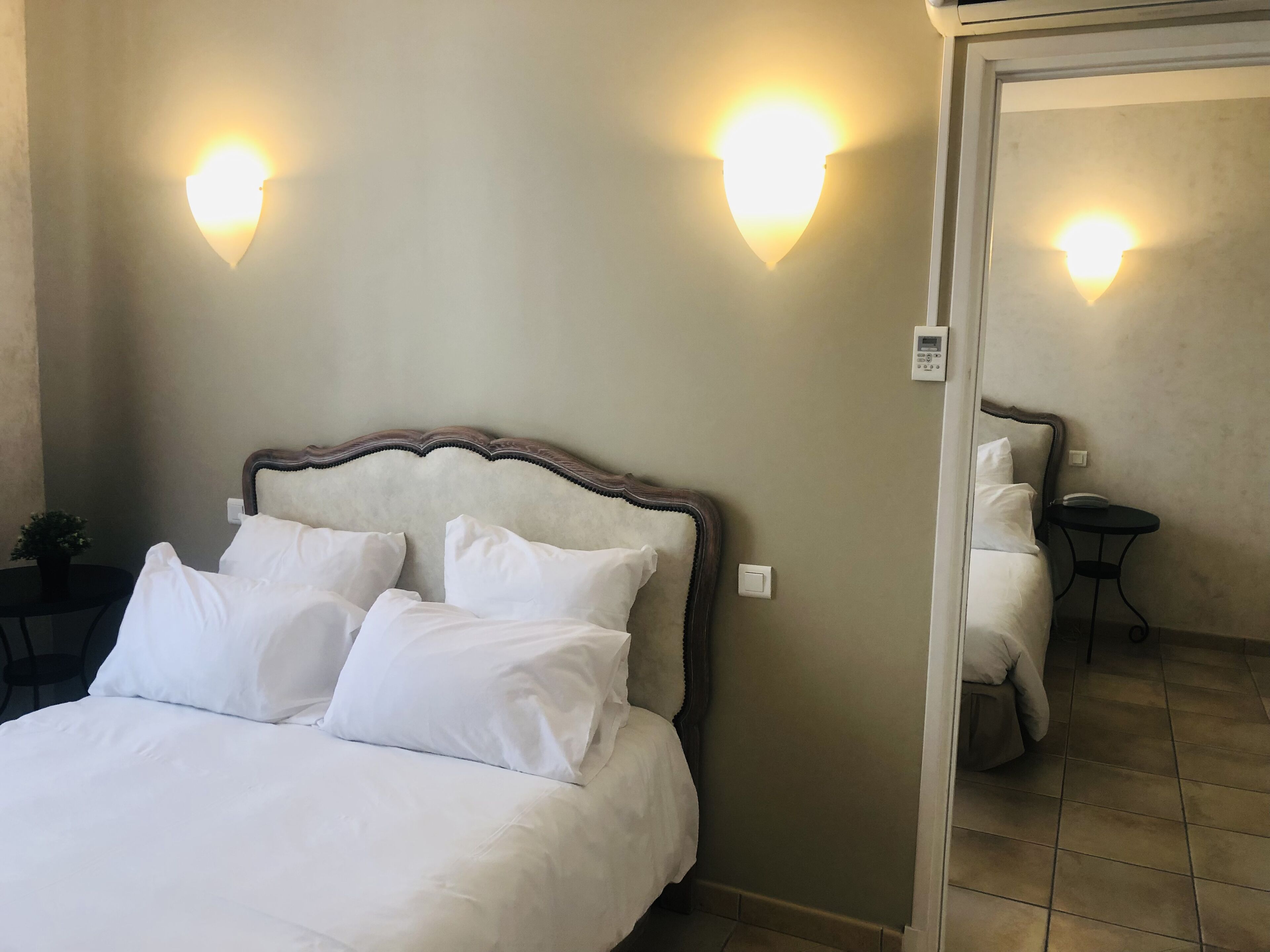 A hotel room with a large bed, two wall-mounted lights, a bedside table, and a small round table.