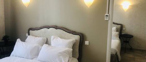 A hotel room with a large bed, two wall-mounted lights, a bedside table, and a small round table.