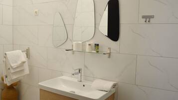Une salle de bain avec un lavabo blanc, un miroir et un porte-serviettes.