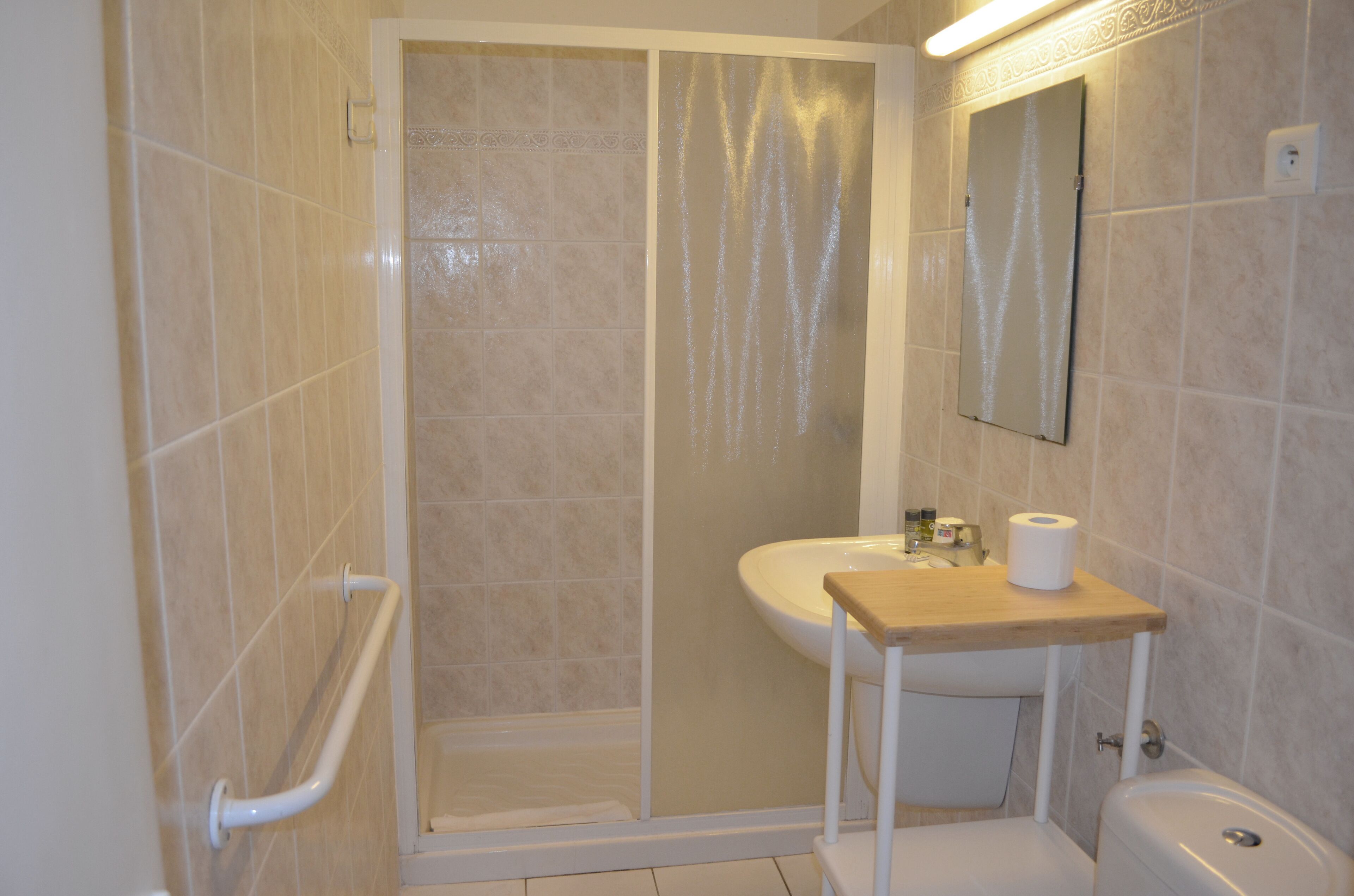 A bathroom with a shower, toilet, sink, and a mirror.