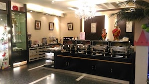 A buffet area with multiple food stations, a glass display case, and a decorative plant. - Beidoo Hotel (Keelung)