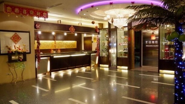 A hotel lobby with a reception desk, a chandelier, and a palm tree decoration. - Beidoo Hotel (Keelung)