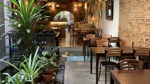Un restaurante con pared de ladrillo, mesas y sillas de madera, y plantas en macetas.