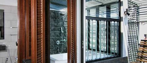 A modern bathroom with a wooden vanity, a glass shower enclosure, and a view of the outside.