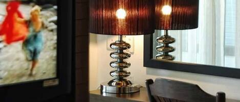 A television displaying an HBO show, a lamp with a spiral base, and a wooden chair.