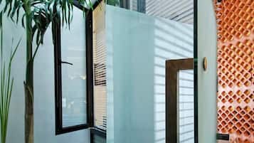 Una habitación moderna con un ventanal grande, una planta en maceta y un muro con textura.