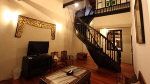 Una sala de estar con televisor de pantalla plana, una mesa de centro y una escalera que sube a un piso superior.