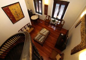 Una habitación con piso de madera, una mesa de comedor con sillas, un sofá, un tapete pequeño y una escalera.