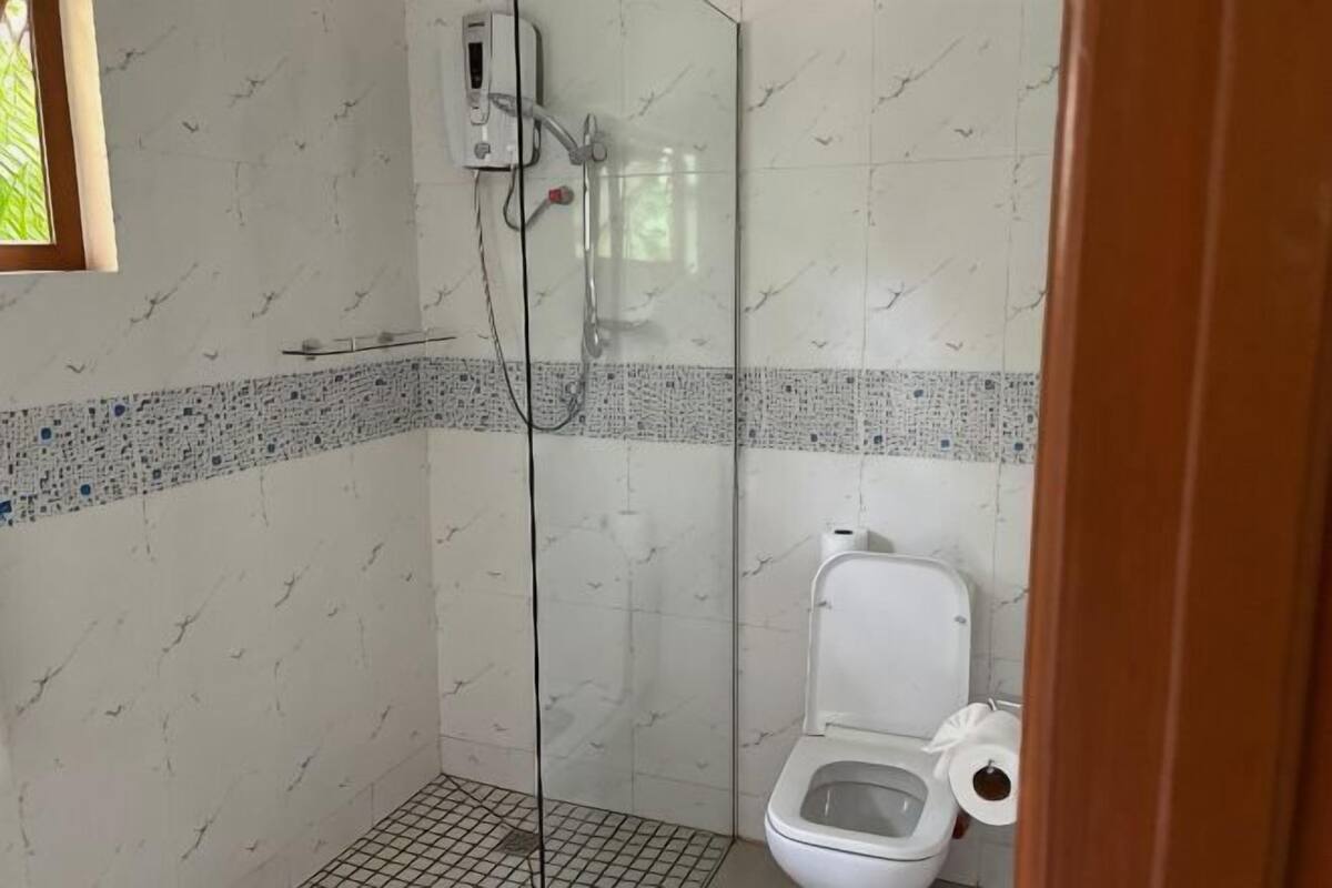 Ein Badezimmer mit Dusche, Toilette und gefliesten Wänden.