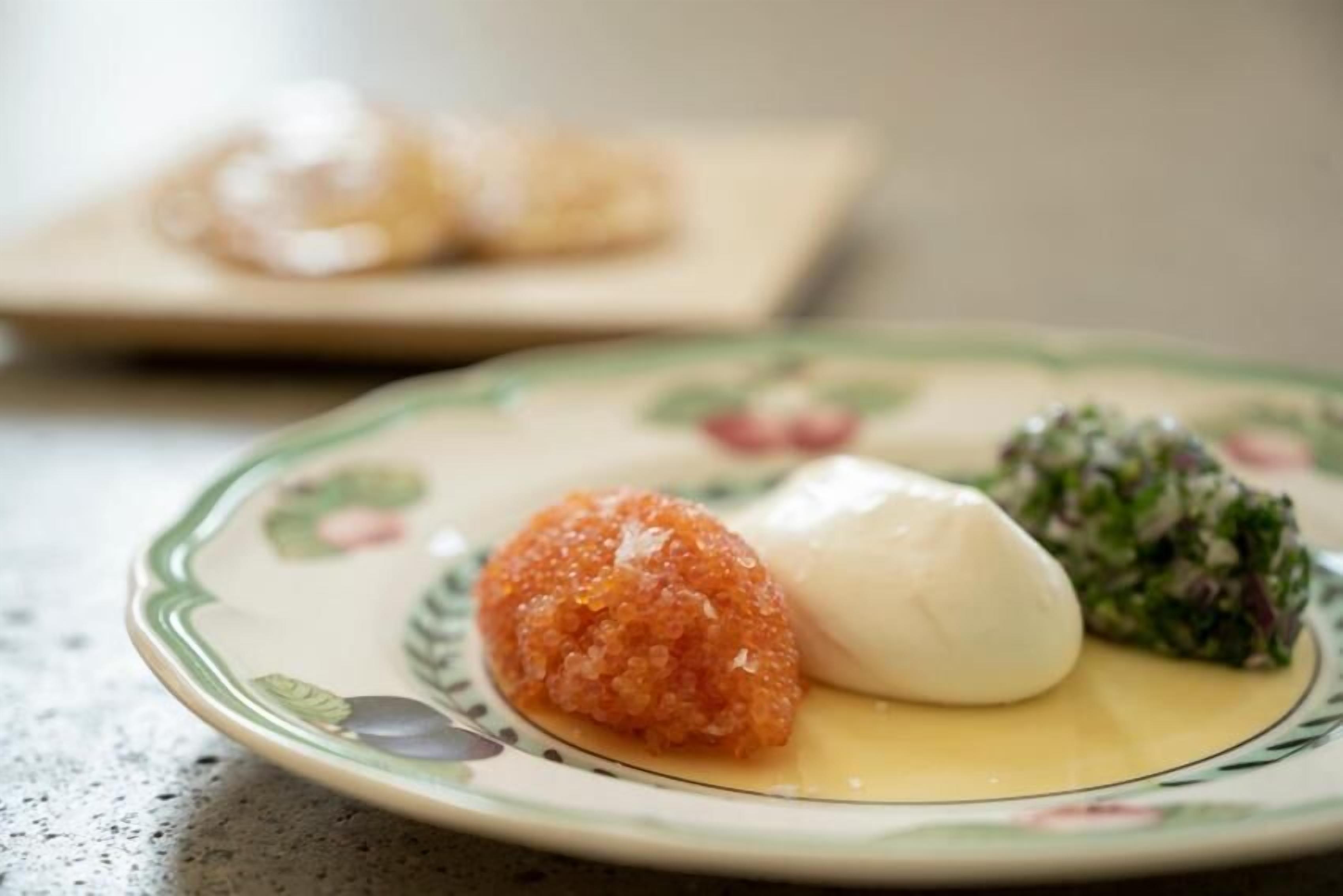 A plate with a white food item, a round orange food item, and a green salad.