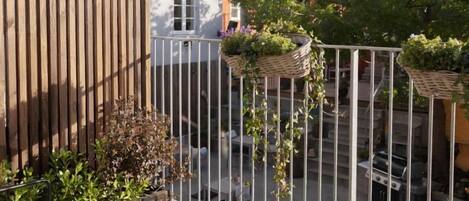 A balcony with a wooden fence, potted plants, and a view of a street.