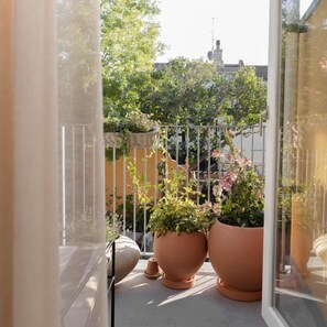 A balcony with potted plants and a view of a building.