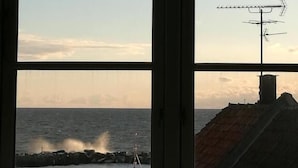 Une fenêtre donnant sur la mer et une côte rocheuse.