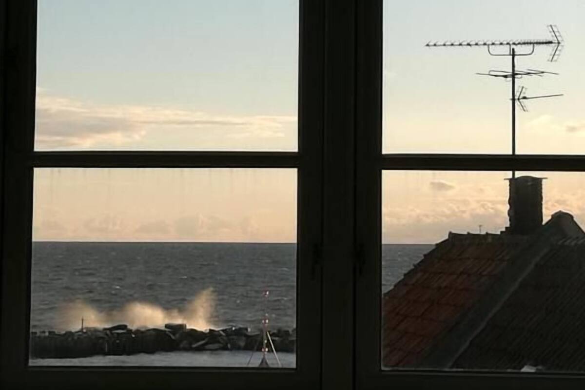 A window with a view of the sea and a rocky shoreline.