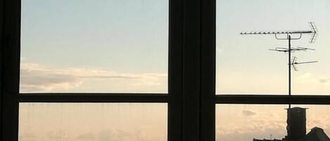 Una ventana con vista al mar y a una costa rocosa.