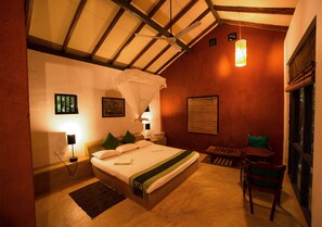 A bedroom with a bed, bedside table, lamp, and a small window.