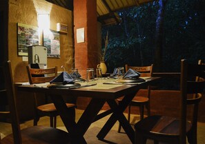 A dining area with a wooden table set for four, surrounded by wooden chairs.